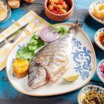 A vibrant Mediterranean meal featuring grilled fish and assorted appetizers on a rustic table.